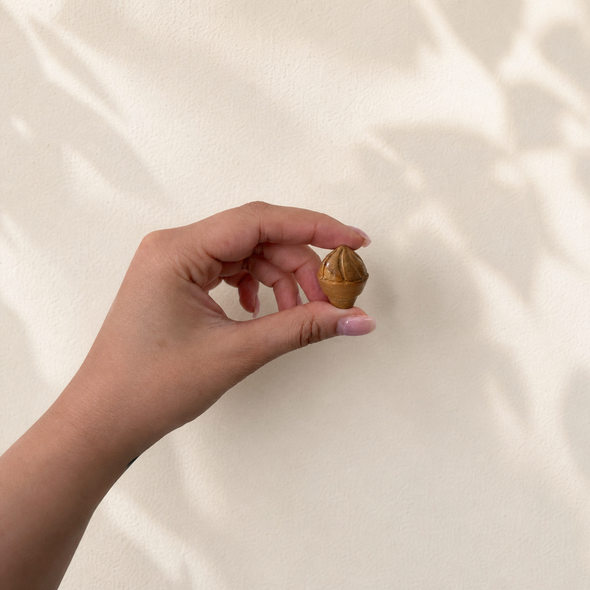Hand holding a Golden Tiger's Eye crystal ice-cream carving to show its petite size