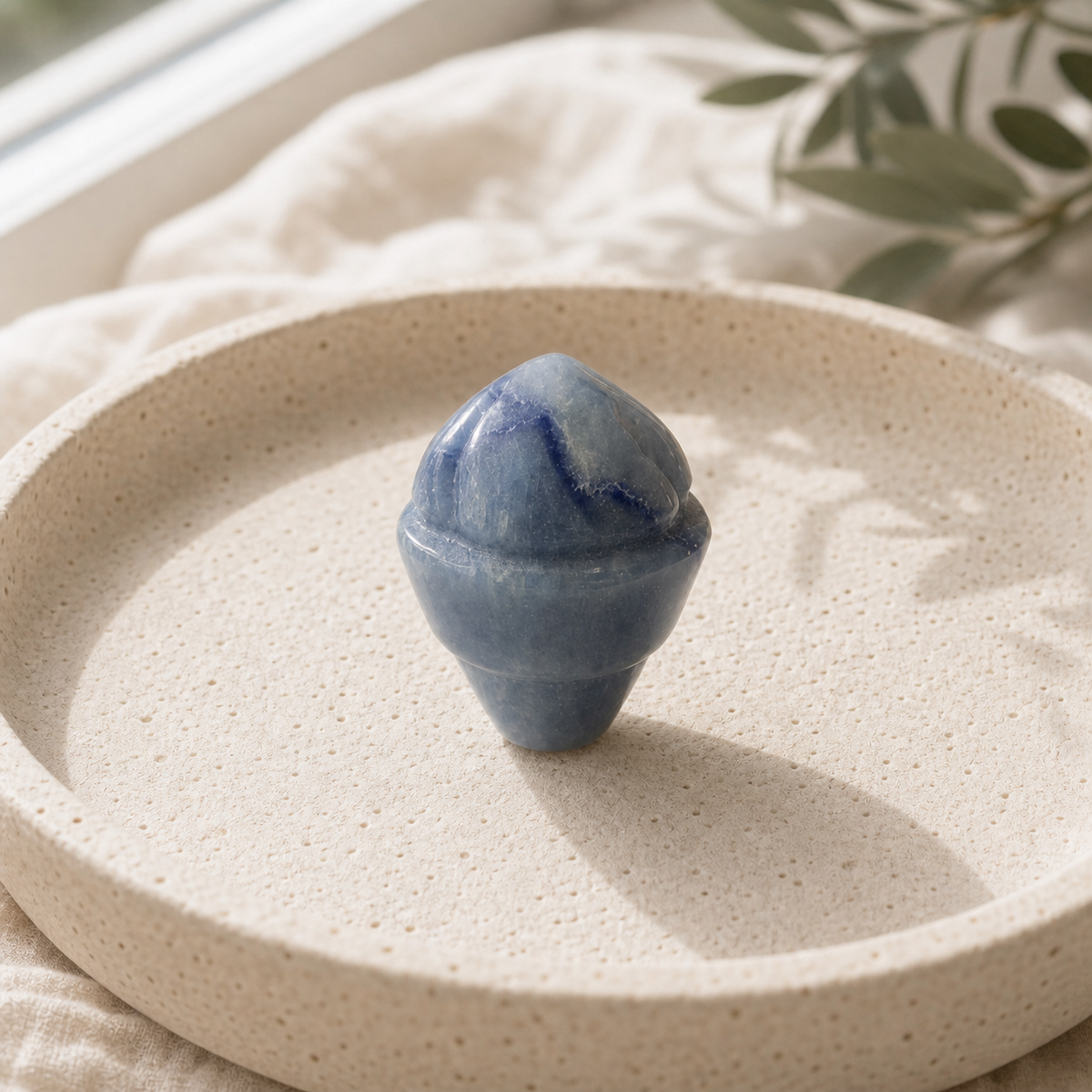 Blue Aventurine crystal ice-cream carving standing on a cream travertine plate