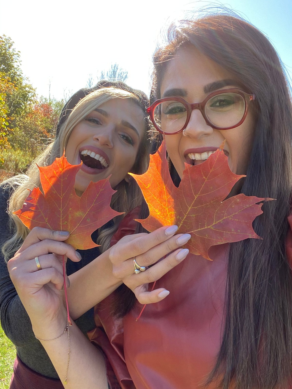 Negar and Yalda outdoors holding autumn maple leaves
