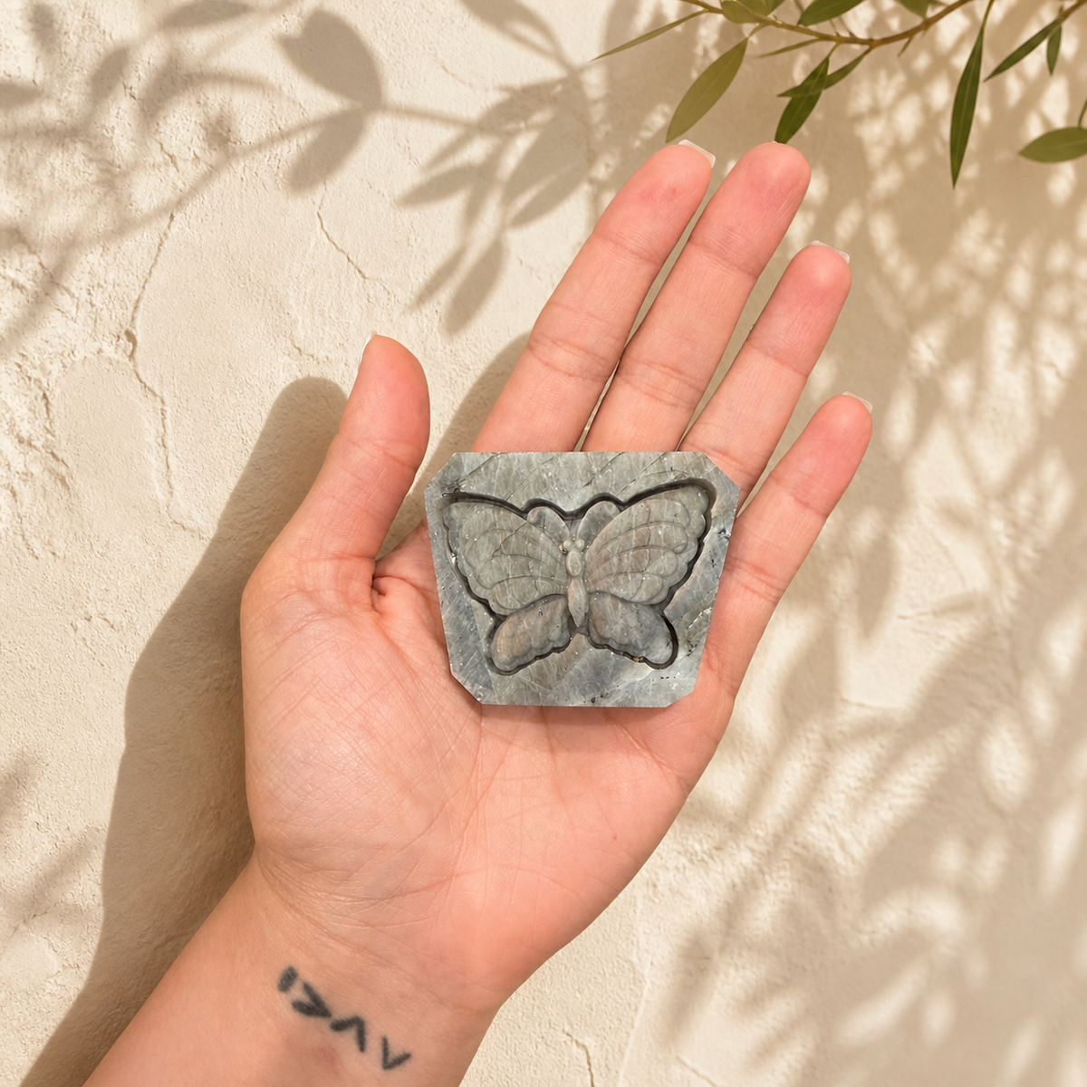 Labradorite butterfly carving held in hand for size reference