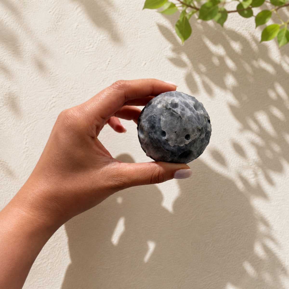 Labradorite moon carving held in hand for size reference