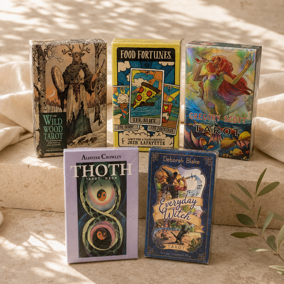 Five sealed Tarot card decks displayed on stone platforms in natural light