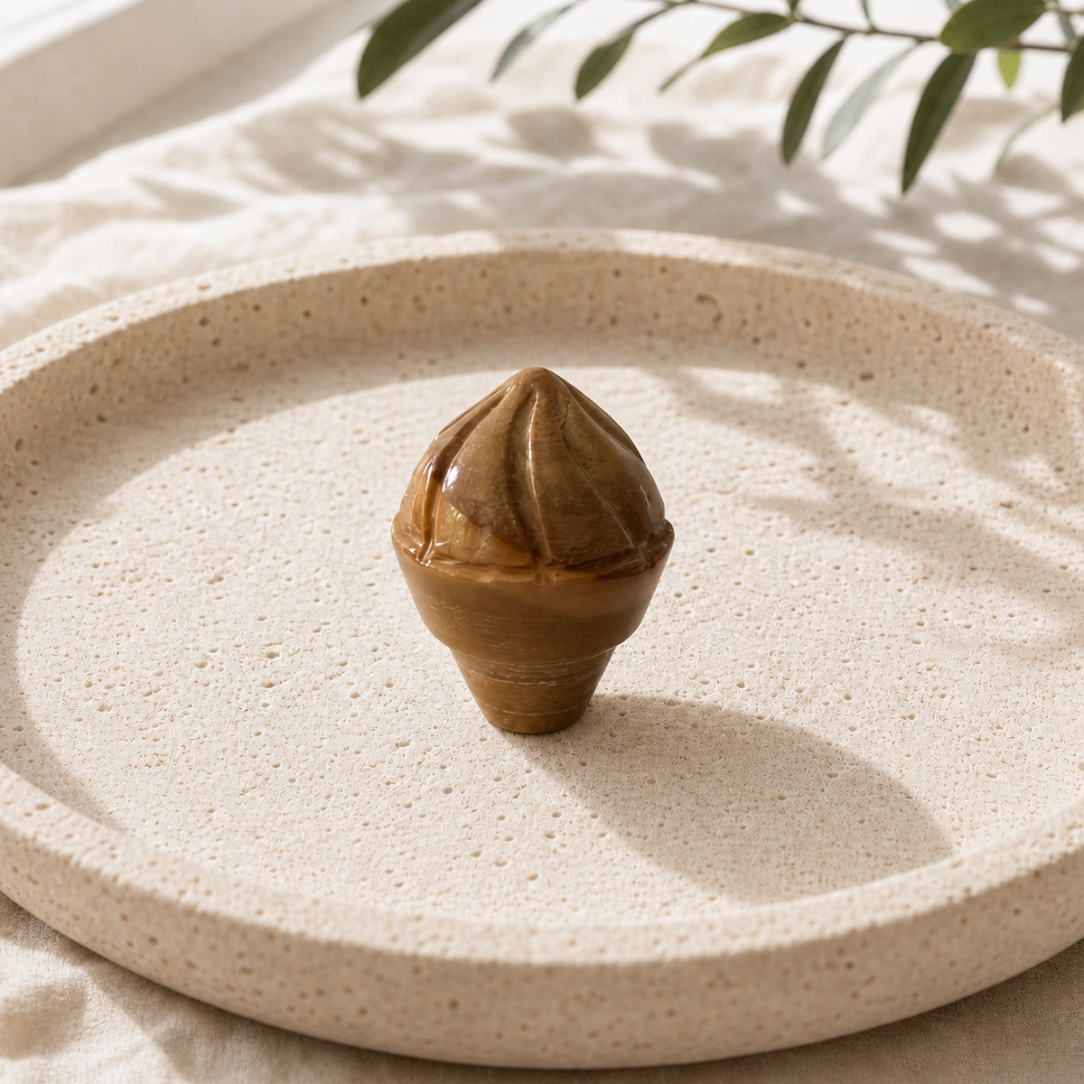 Golden Tiger's Eye crystal ice-cream carving standing on a cream travertine plate