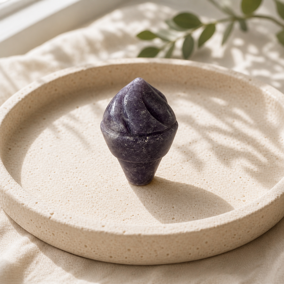Purple Aventurine crystal ice-cream carving standing on a cream travertine plate