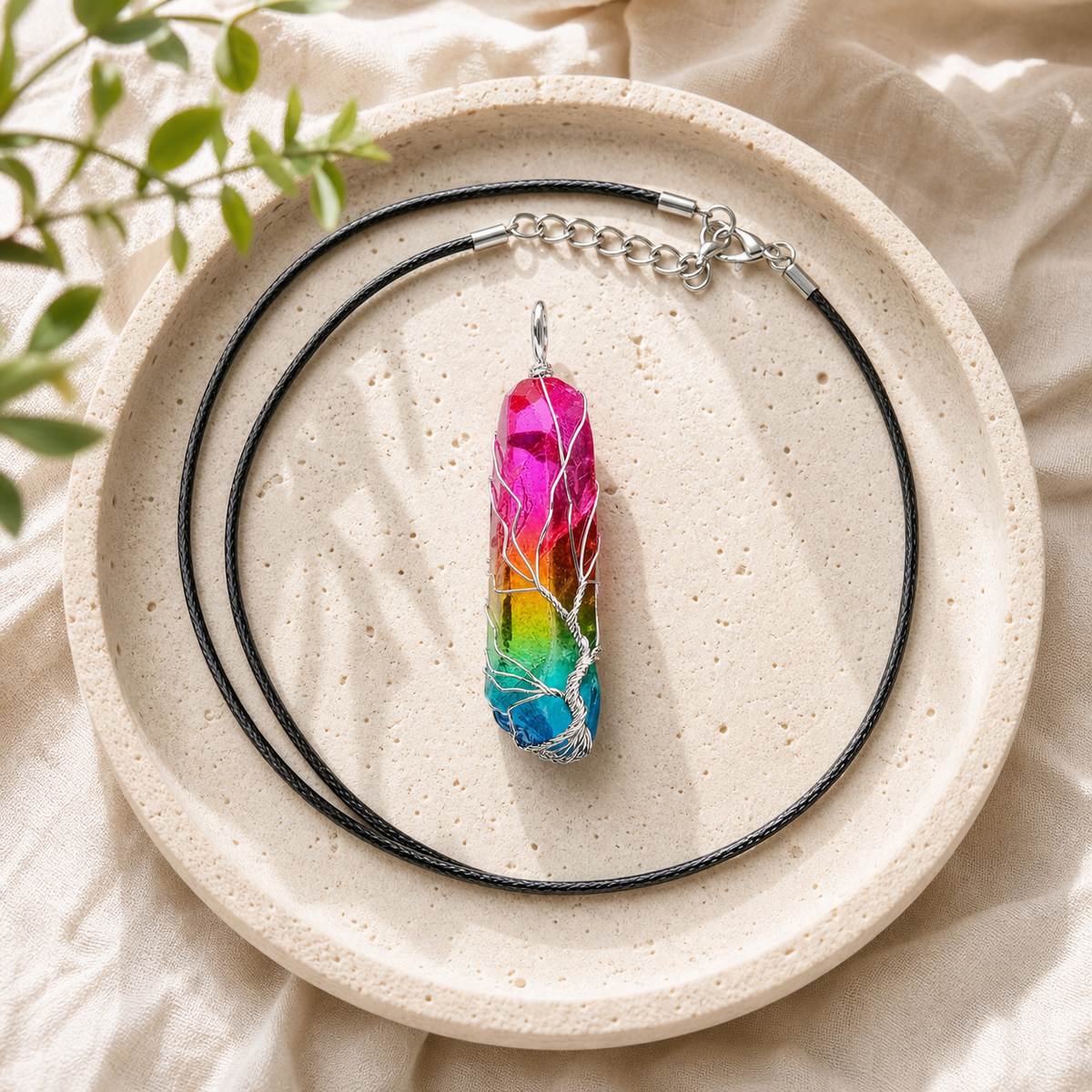 Rainbow Quartz Tree of Life pendant and black cord on a round stone plate