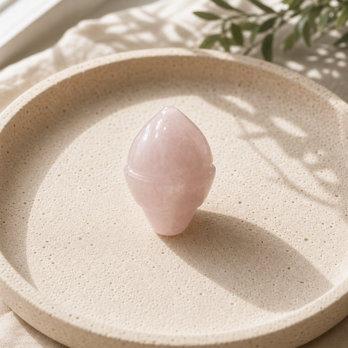 Rose Quartz crystal ice-cream carving standing on a cream travertine plate