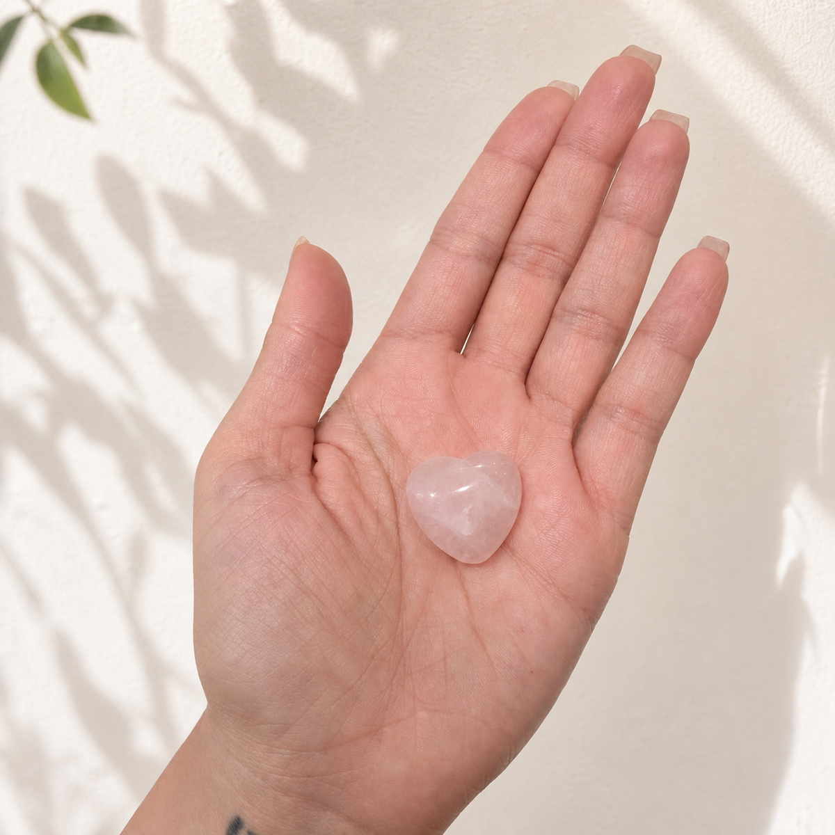Small Rose Quartz heart carving resting in a hand for scale