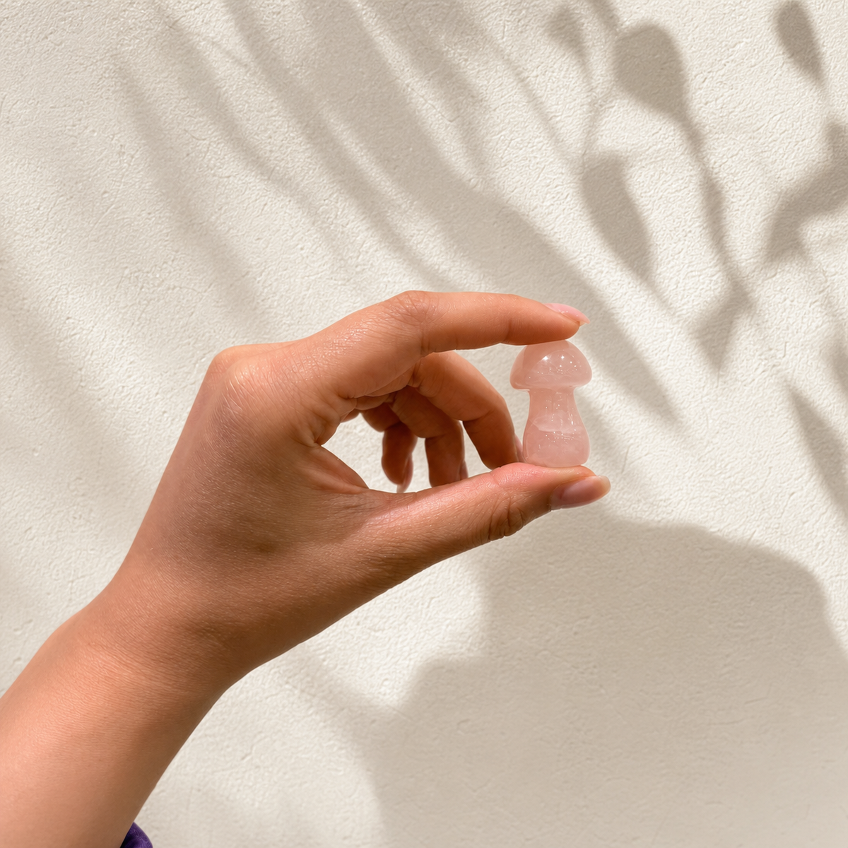 Small Rose Quartz mushroom carving held in a hand for size reference
