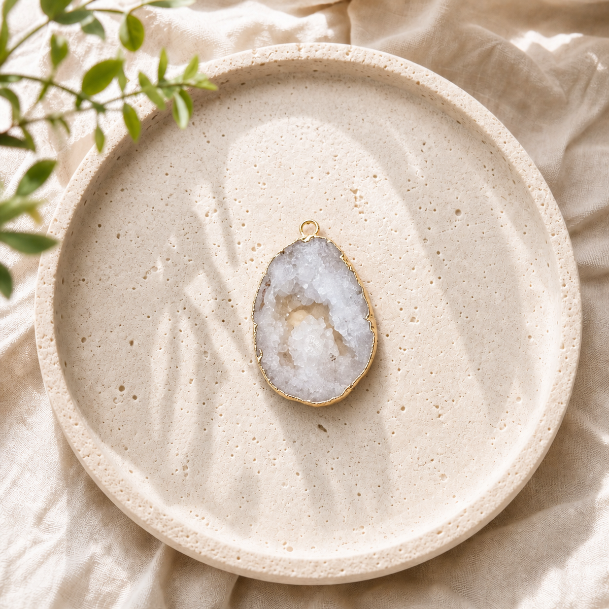 Gold-plated White Druzy Agate pendant displayed on a round stone plate