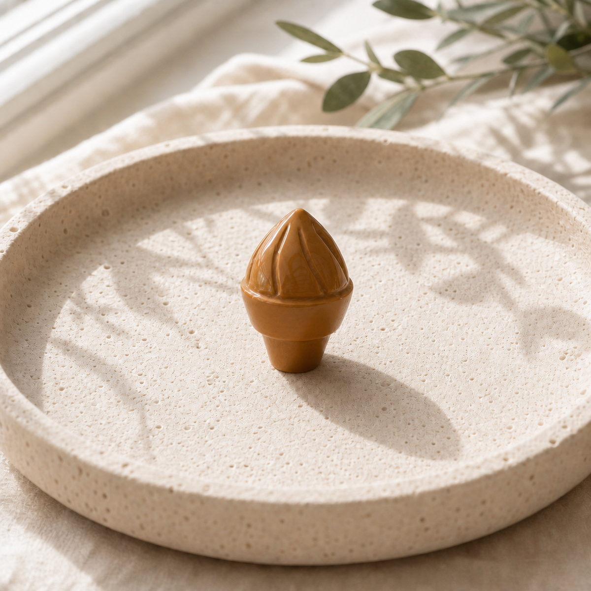 Yellow Jasper crystal ice-cream carving standing on a cream travertine plate
